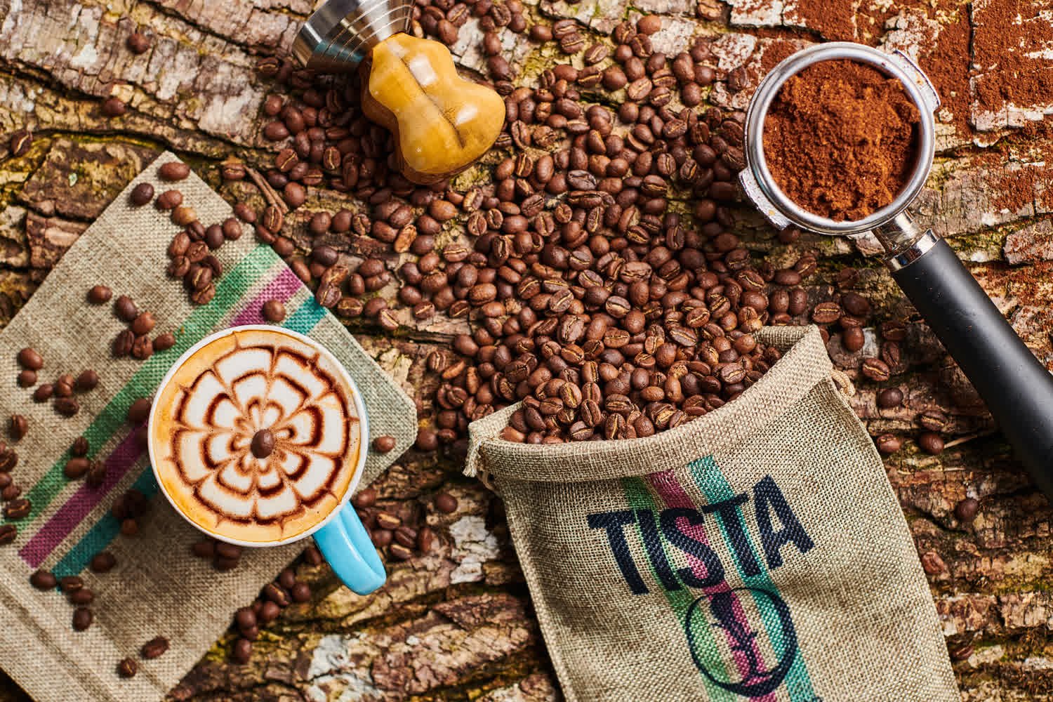 Cenital con latte art, saco de la marca, portafiltro y granos