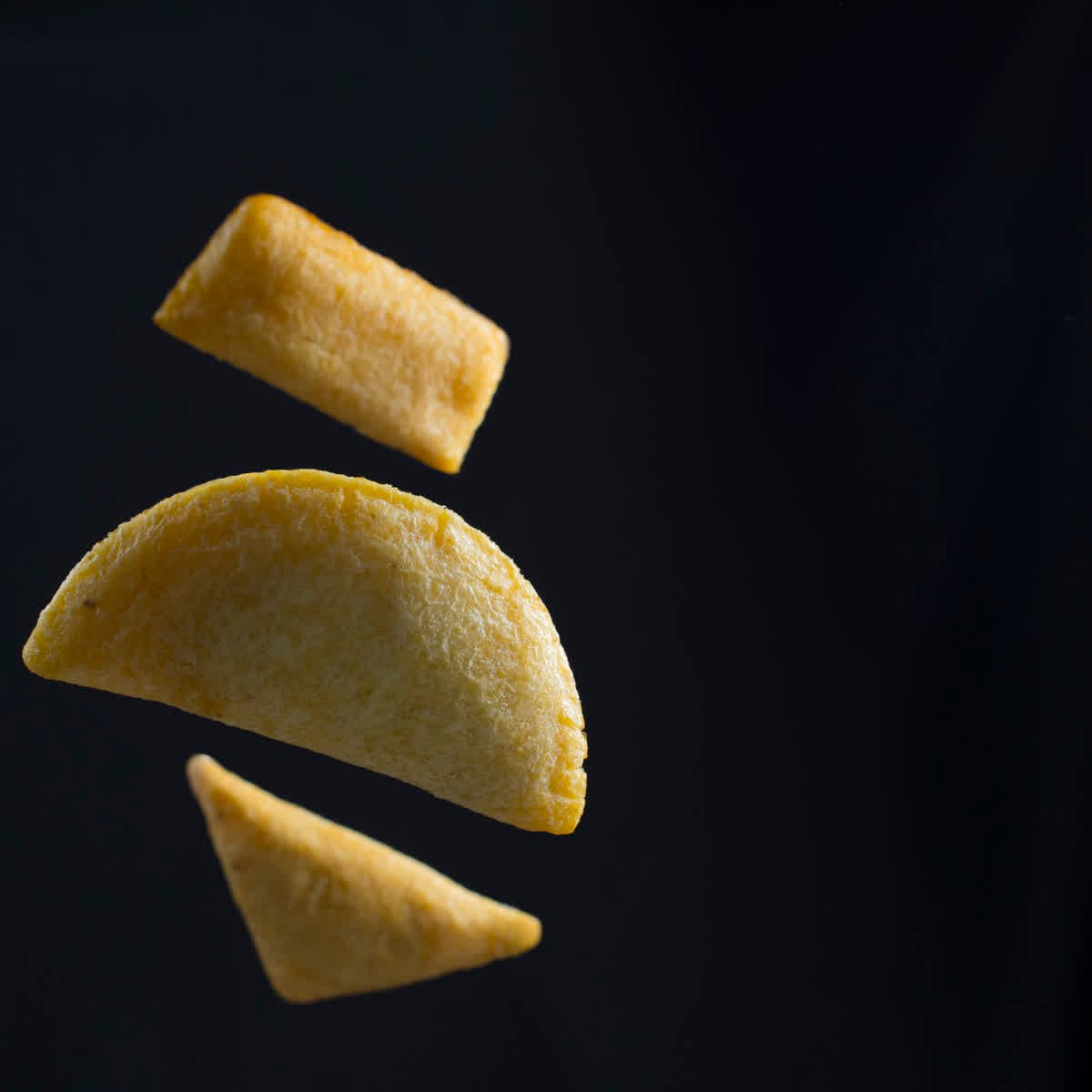 Tres empanadas suspendidas sobre fondo negro
